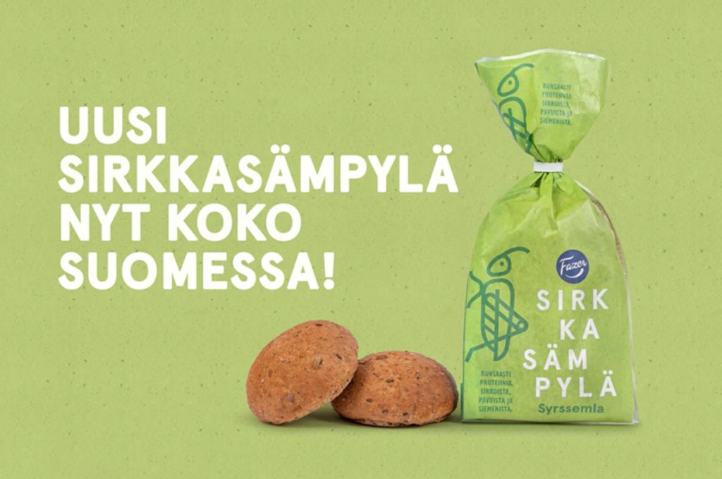 Mainoskuva Fazerin sirkkasämpylästä, jossa sämpyläpussi, kaksi sämpylää ja mainoslause vihreää taustaa vasten.