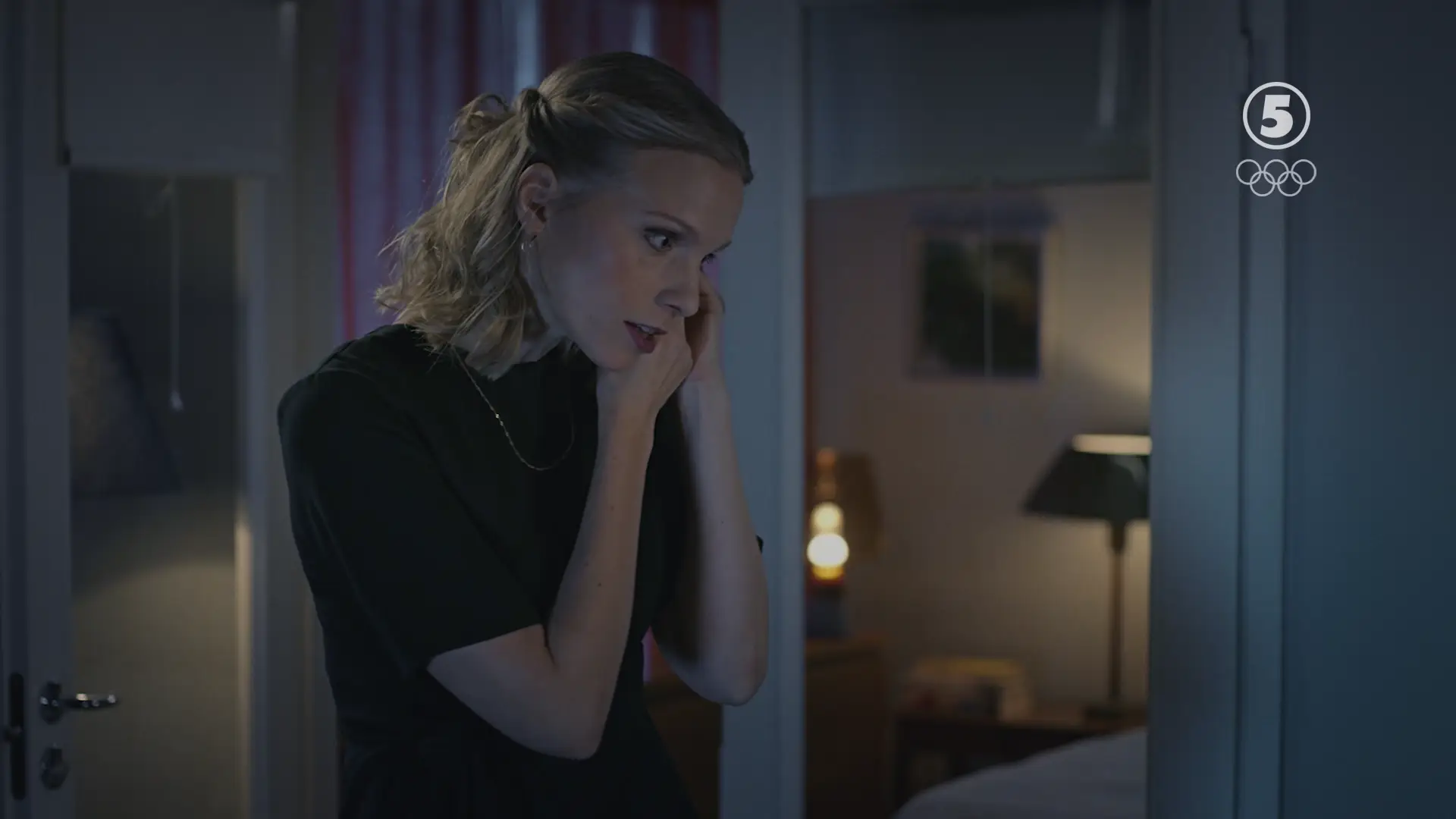 Nainen laittaa korvakorua korvaan ja puhuu samalla. Lopuksi nostaa katseensa ylöspäin. Video looppi.