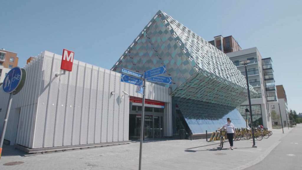 Espoon metroasema ulkopuolelta. Punainen metrokyltti ja vaalea rakennus.