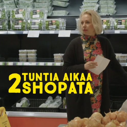 Krisse Salminen seisoo ruokakaupassa paperi kädessä. Etualalla teksti "2 tuntia aikaaa shopata".