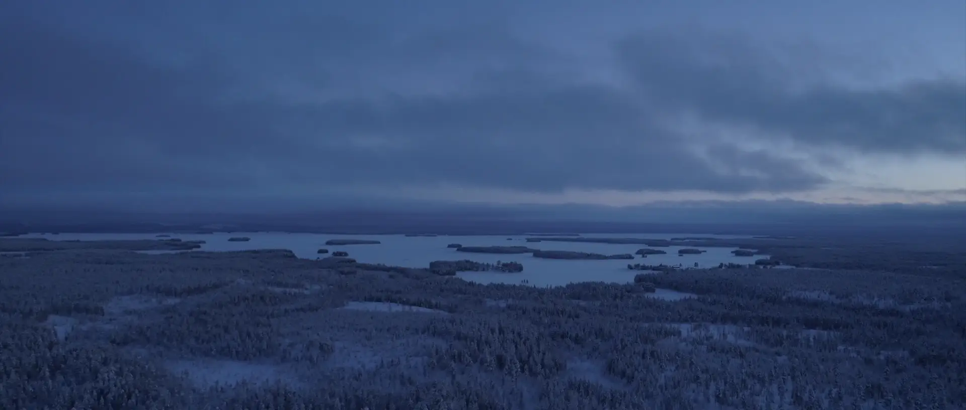 Laajakuva talvisesta järvimaisemasta revontulilla. Prosessikuva ennen ja jälkeen jälkikäsittelyn. Videolooppi.