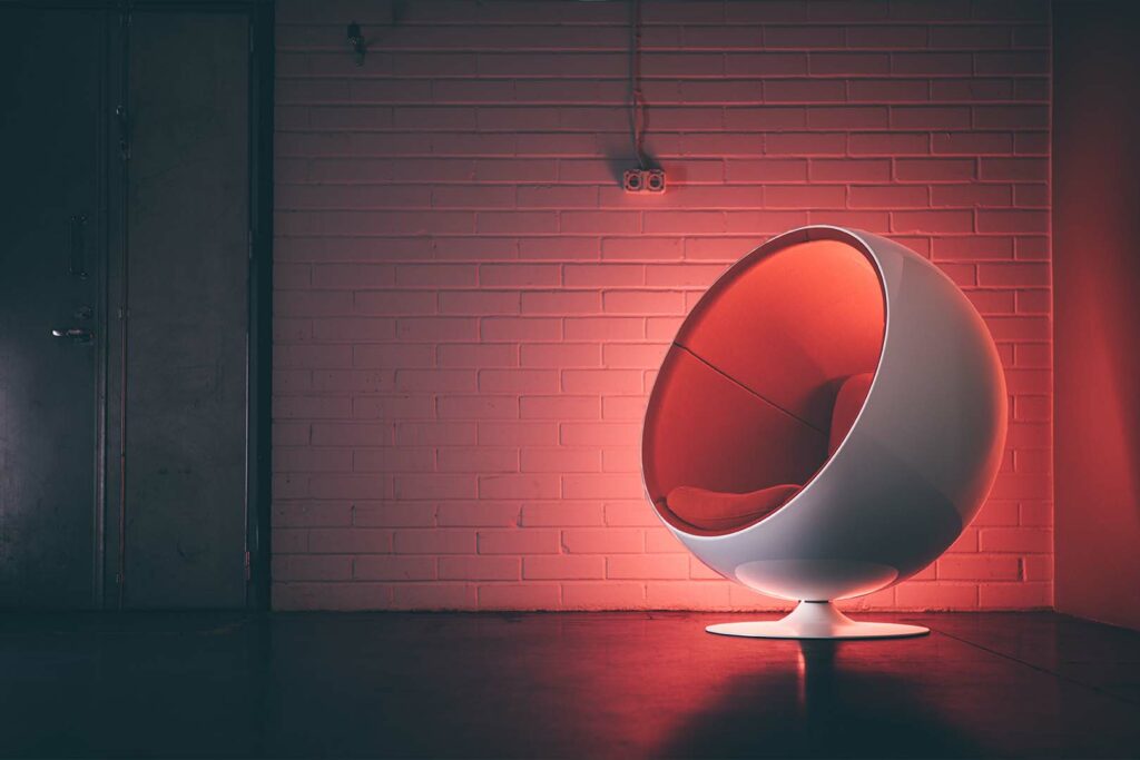 Eero Aarnion suunnittelema valkoinen pallotuoli punaisella sisustalla seisoo tyhjässä hallissa.