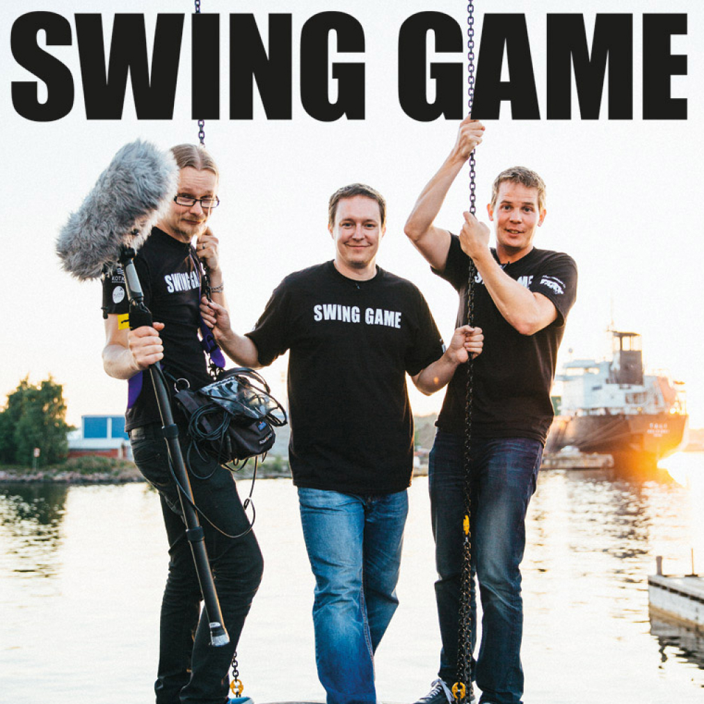 Behind the scenes Ylelle kuvatusta dokumetista. Kolme miestä Swing Game t-paidoissa katsoo hymyille kohti kameraa.
